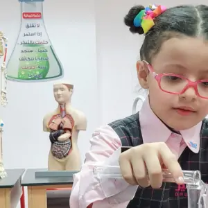 "طالبة تجري تجارب علمية في معمل العلوم بتركيز واهتمام."